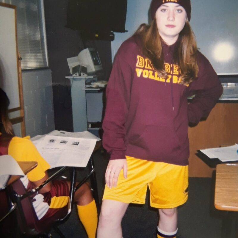 a high school students stands with maroon and gold.