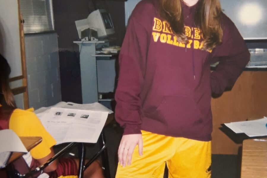 a high school students stands with maroon and gold.