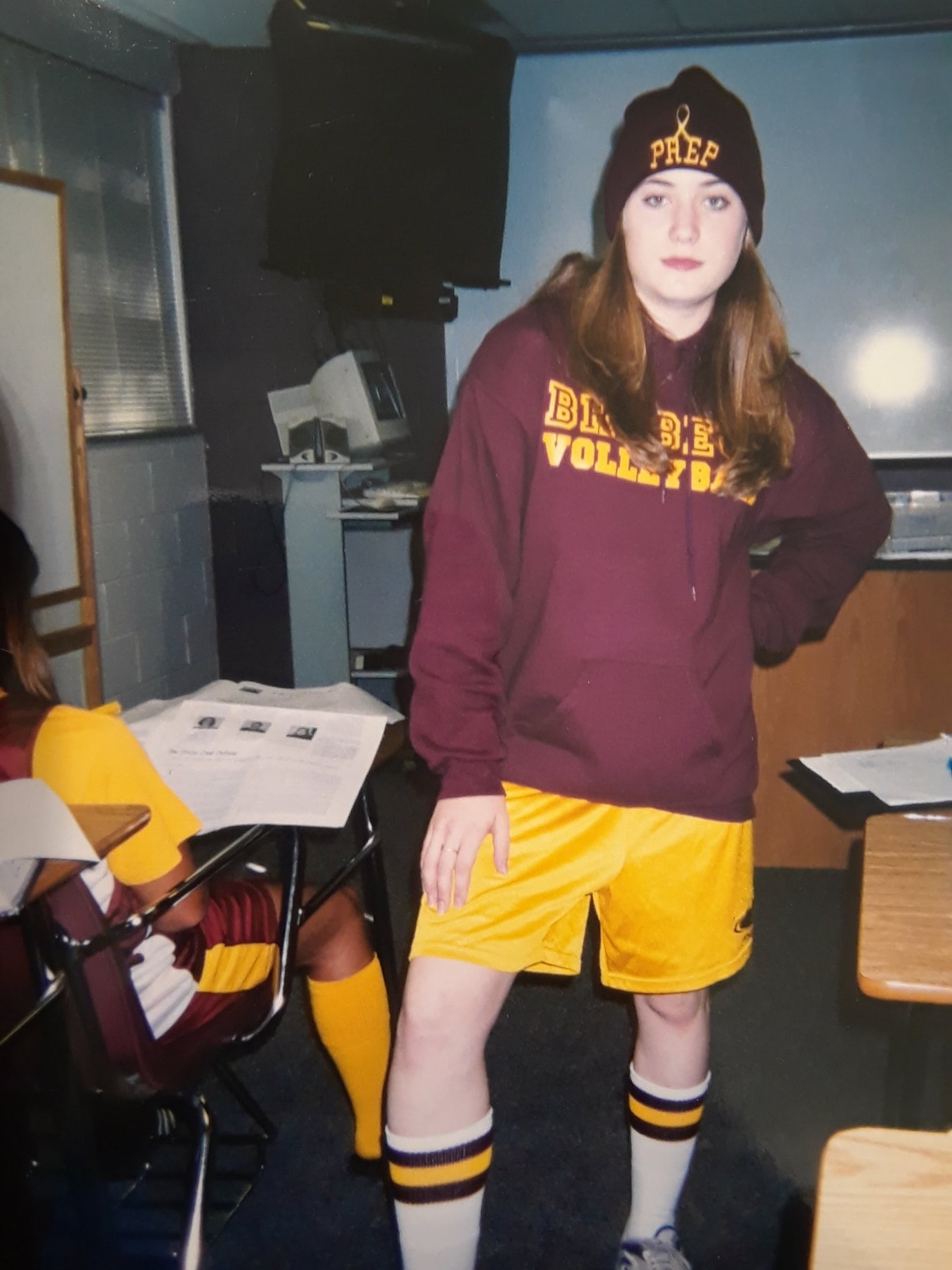 a high school students stands with maroon and gold.