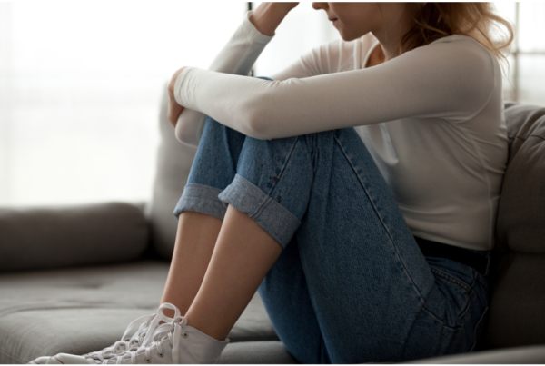 a woman with jeans sits thinking